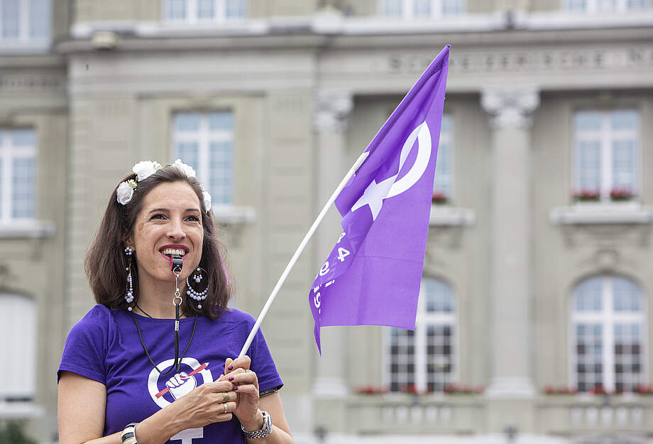 Une femme avec le drapeu de la Grèves des femmes*