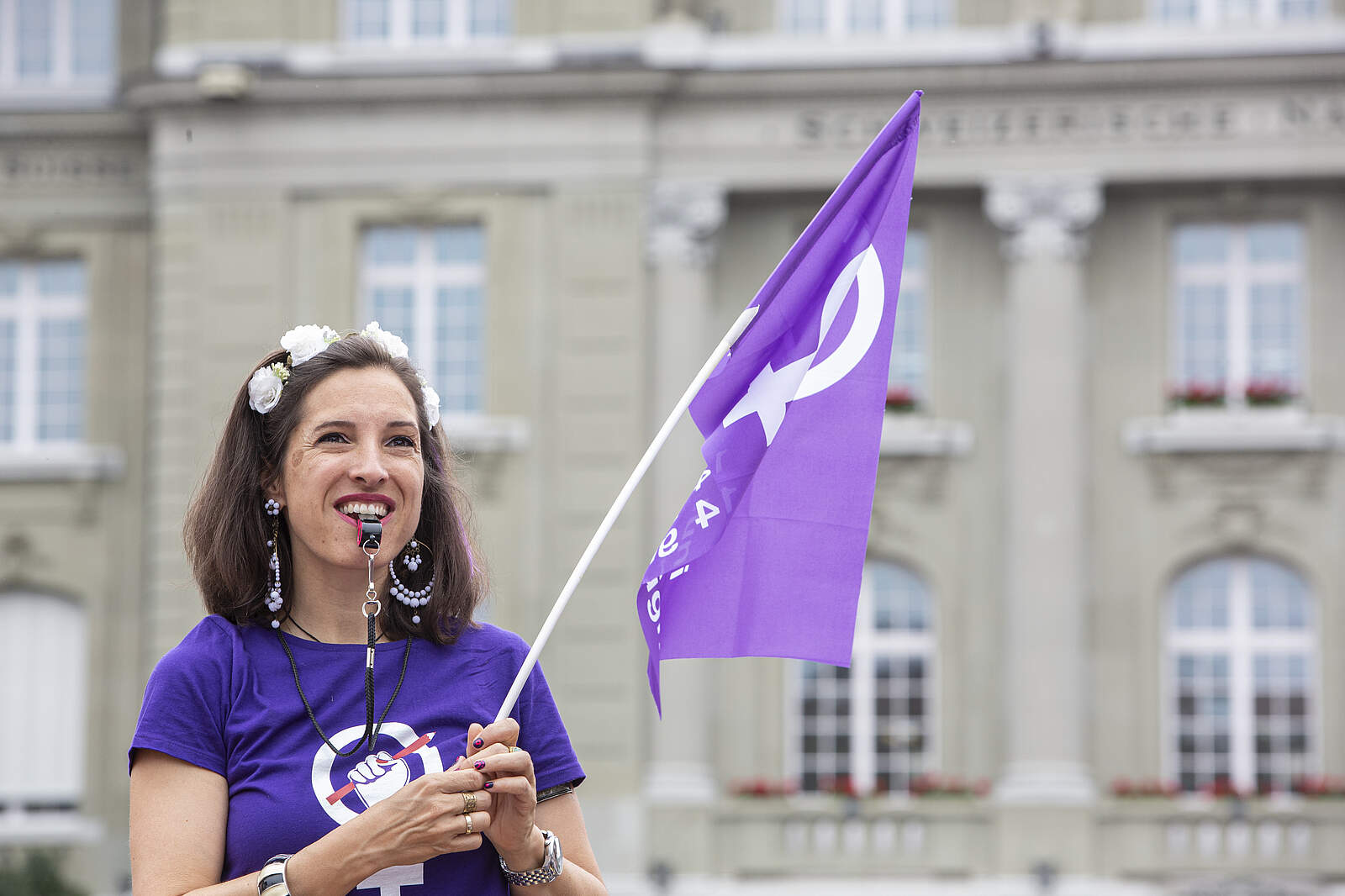 Femme avec un drapeau de la Grève des femmes* et un sifflet