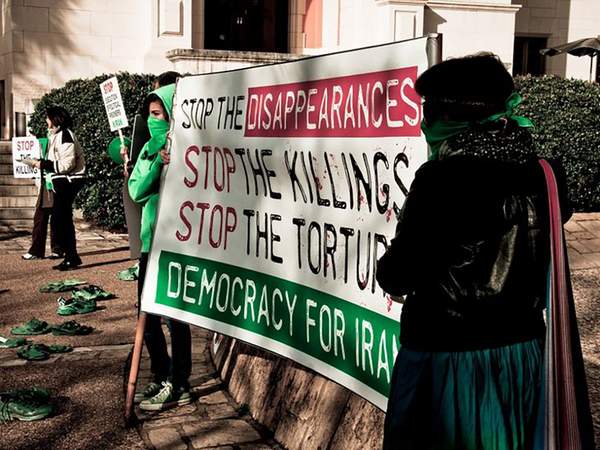 Des femmes brandissent une banderole contre la torture et les meurtres commis par l'État en Iran.