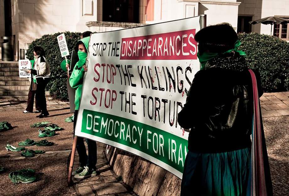 Des femmes brandissent une banderole contre la torture et les meurtres commis par l'État en Iran.