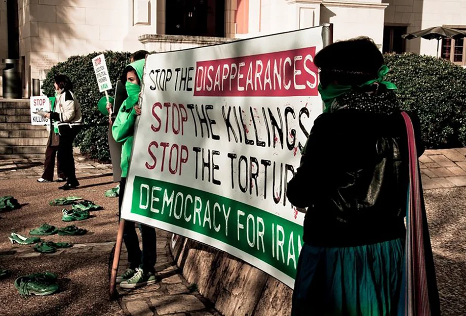 Des femmes brandissent une banderole contre la torture et les meurtres commis par l'État en Iran.