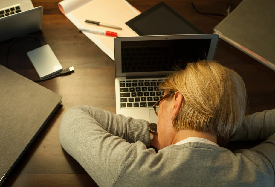 Totalement surmenée Une femme s'endort sur son ordinateur portable