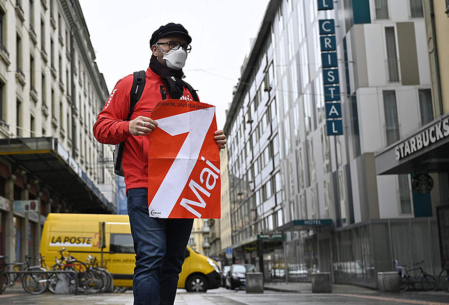 1er mai 3021 : manifestant portant masque FFP2 et affiche du 1er mai dans une route vide de Genève