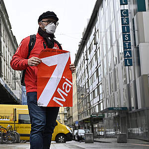 1er mai 3021 : manifestant portant masque FFP2 et affiche du 1er mai dans une route vide de Genève
