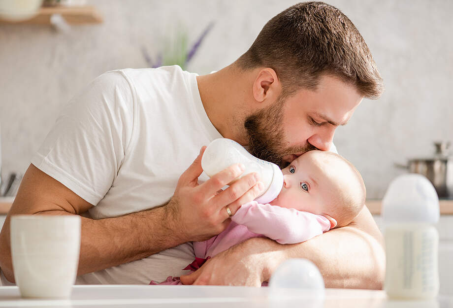 Un père donne du lait à son bébé.