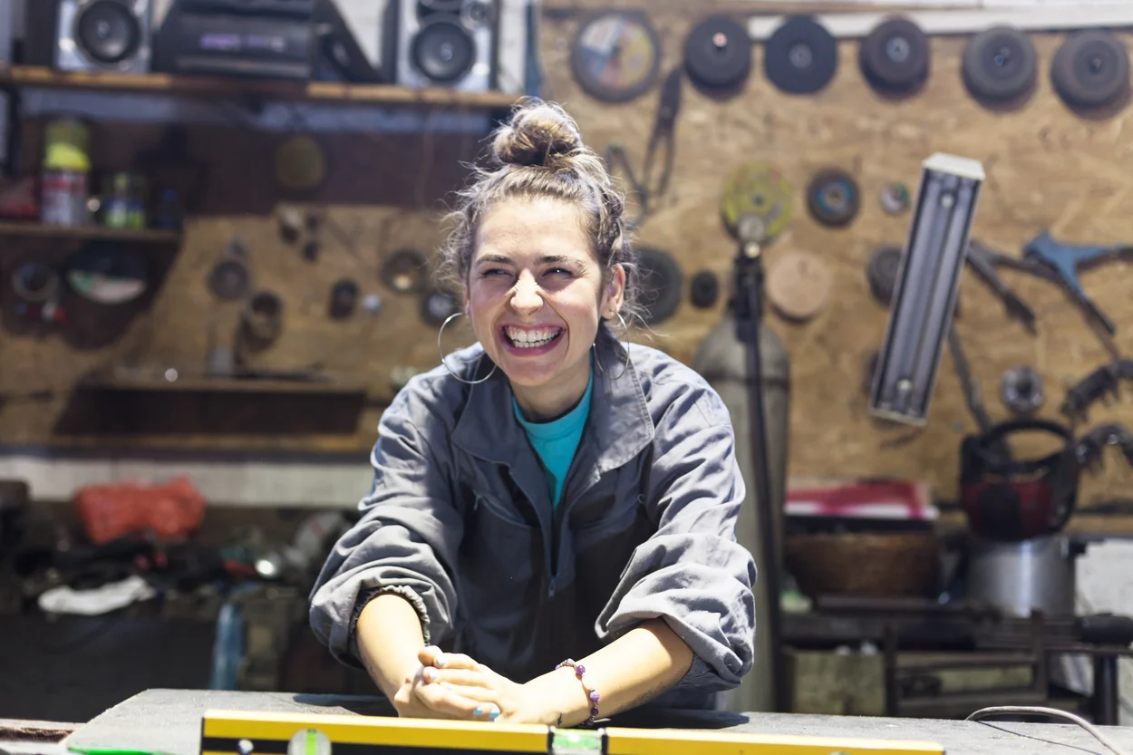 Apprentie au travail Jeune femme qui rit dans l'atelier