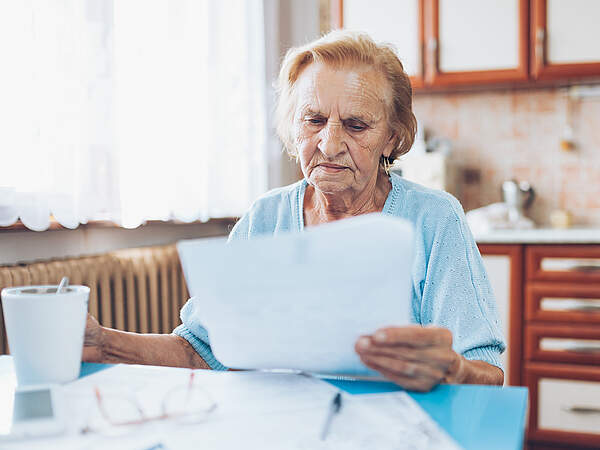 une femme agée avec beaucoup de factures