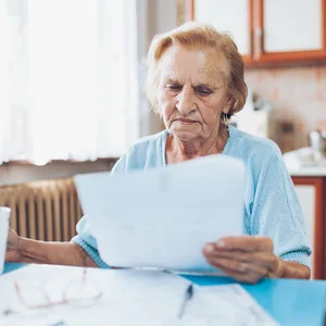 une femme agée avec beaucoup de factures