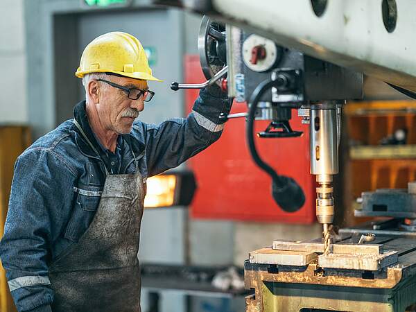 Travailleur plus âgé travaillant avec une machine dans l'usine