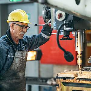 Travailleur plus âgé travaillant avec une machine dans l'usine
