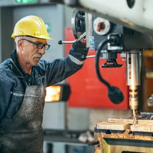 Travailleur plus âgé Travailleur plus âgé travaillant avec une machine dans l'usine