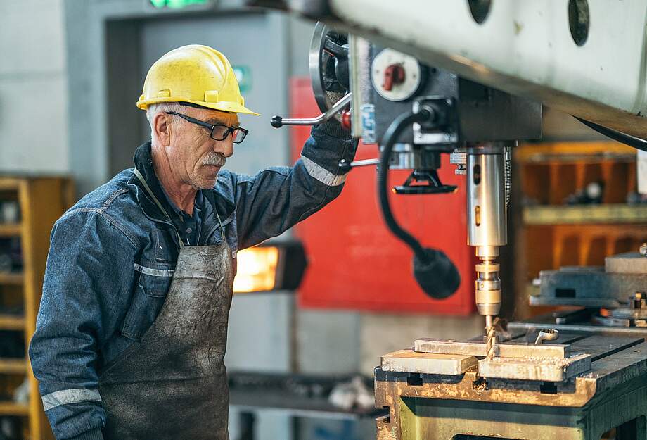 Travailleur plus âgé travaillant avec une machine dans l'usine