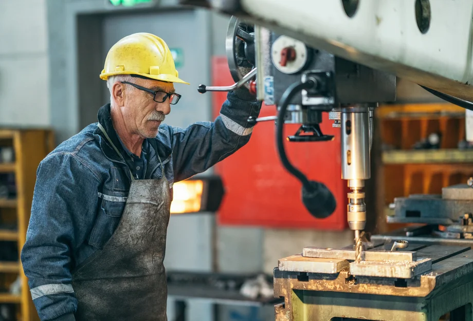 Travailleur plus âgé Travailleur plus âgé travaillant avec une machine dans l'usine