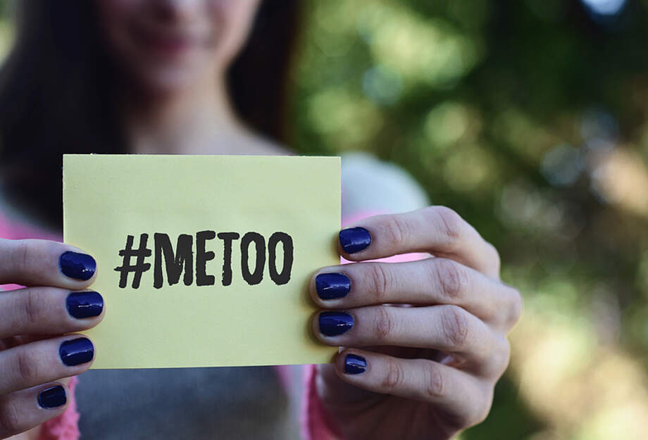 Une femme présent un morceau de papier avec #metoo