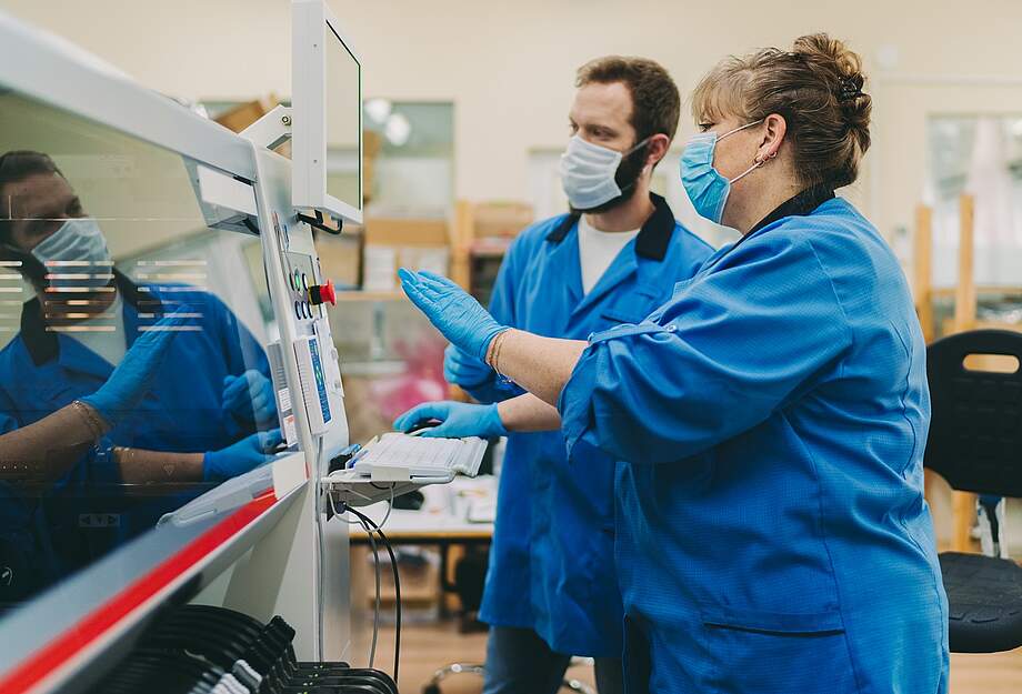 Deux employé-e-s portant un masque de protection utilisent une machine