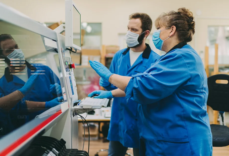 Deux employé-e-s portant un masque de protection utilisent une machine