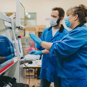 Deux employé-e-s portant un masque de protection utilisent une machine