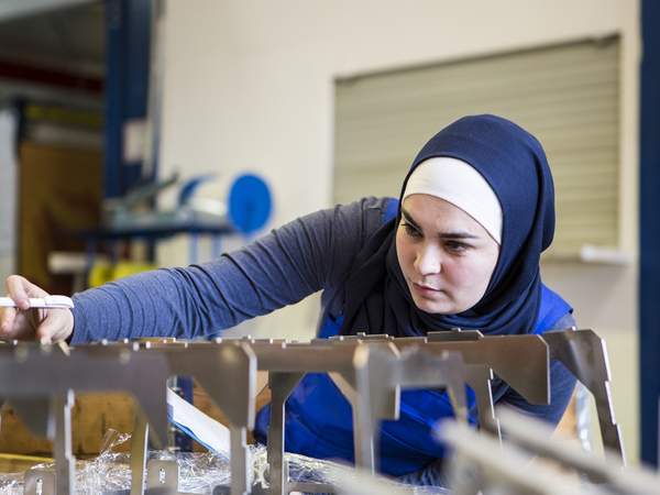Une apprentie avec un foulard fait un contrôle de qualité