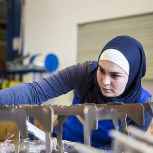Une apprentie avec un foulard fait un contrôle de qualité