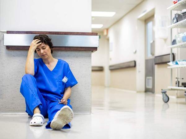 Une infirmière épuisée, allongée sur le sol