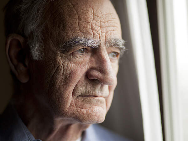 Un vieil homme regarde par la fenêtre.
