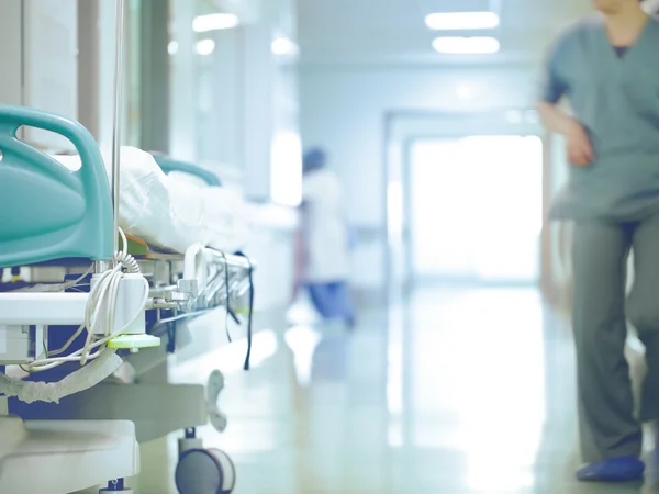 Vue d'un couloir d'hôpital avec un lit et un soignant