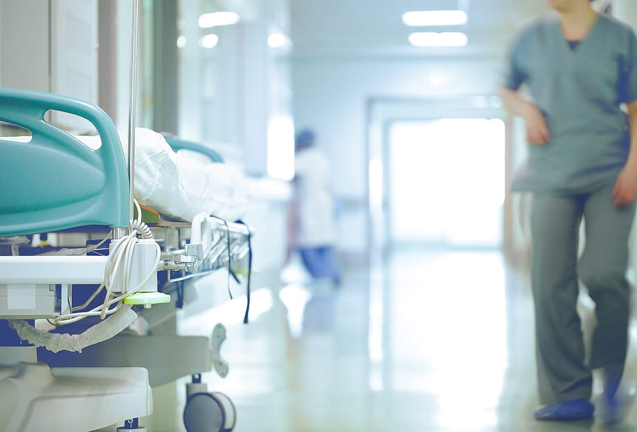 Vue d'un couloir d'hôpital avec un lit et un soignant 