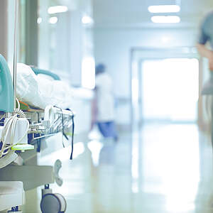 Vue d'un couloir d'hôpital avec un lit et un soignant 