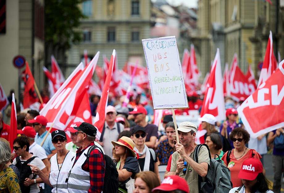 Photo du cortège avec une affiche "Rendez-nous l'argent"